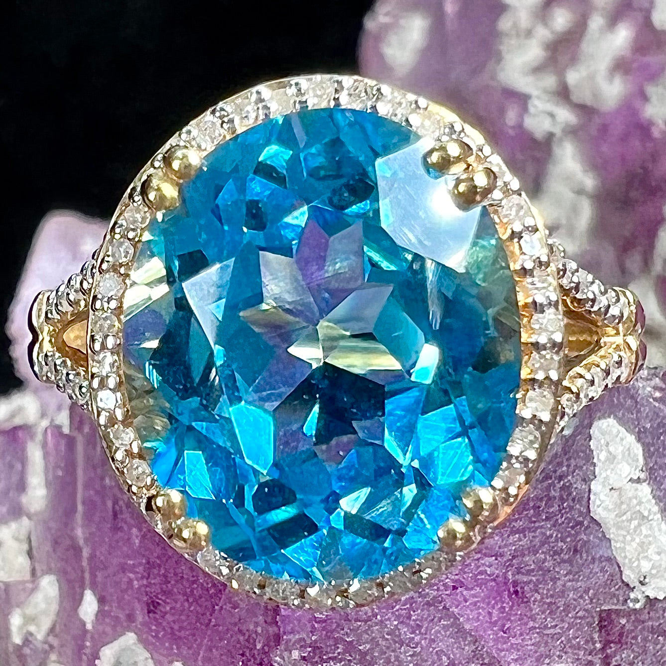 An oval cut Swiss blue topaz and diamond pave split shank ring in yellow gold.