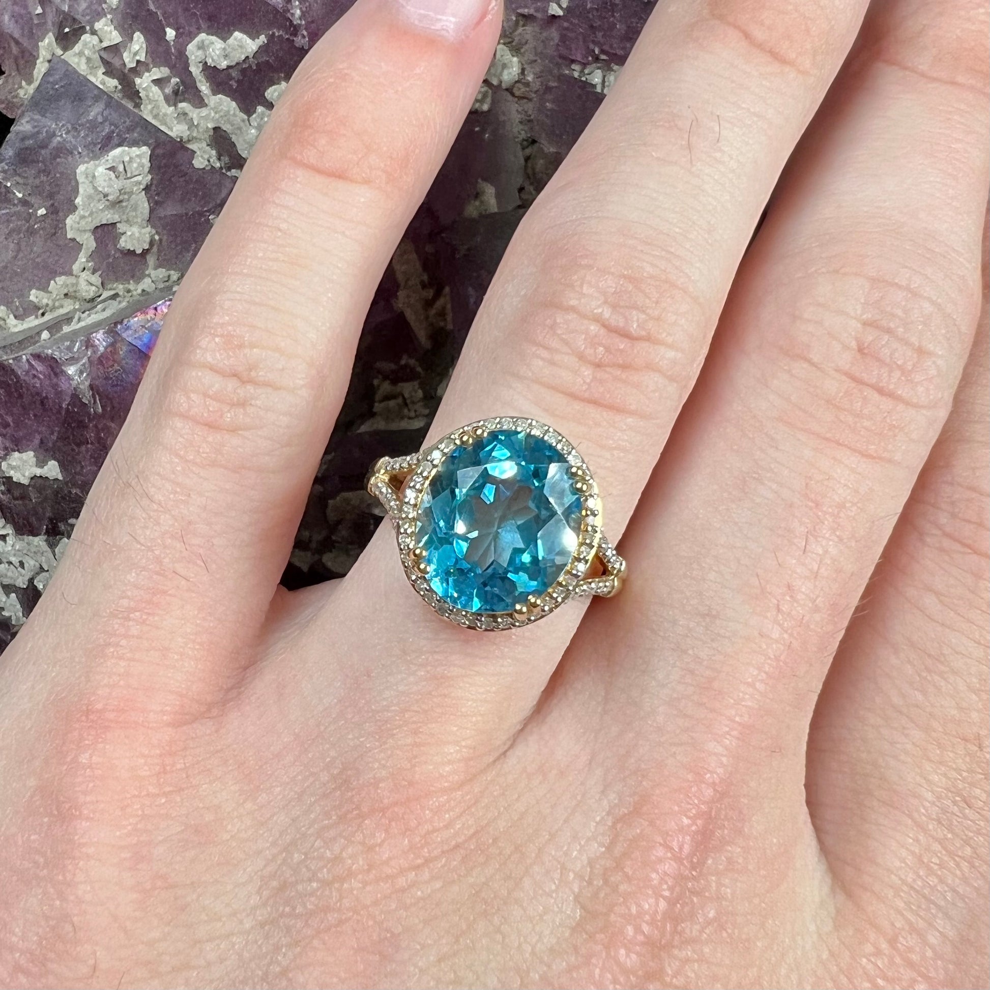 An oval cut Swiss blue topaz and diamond pave split shank ring in yellow gold.