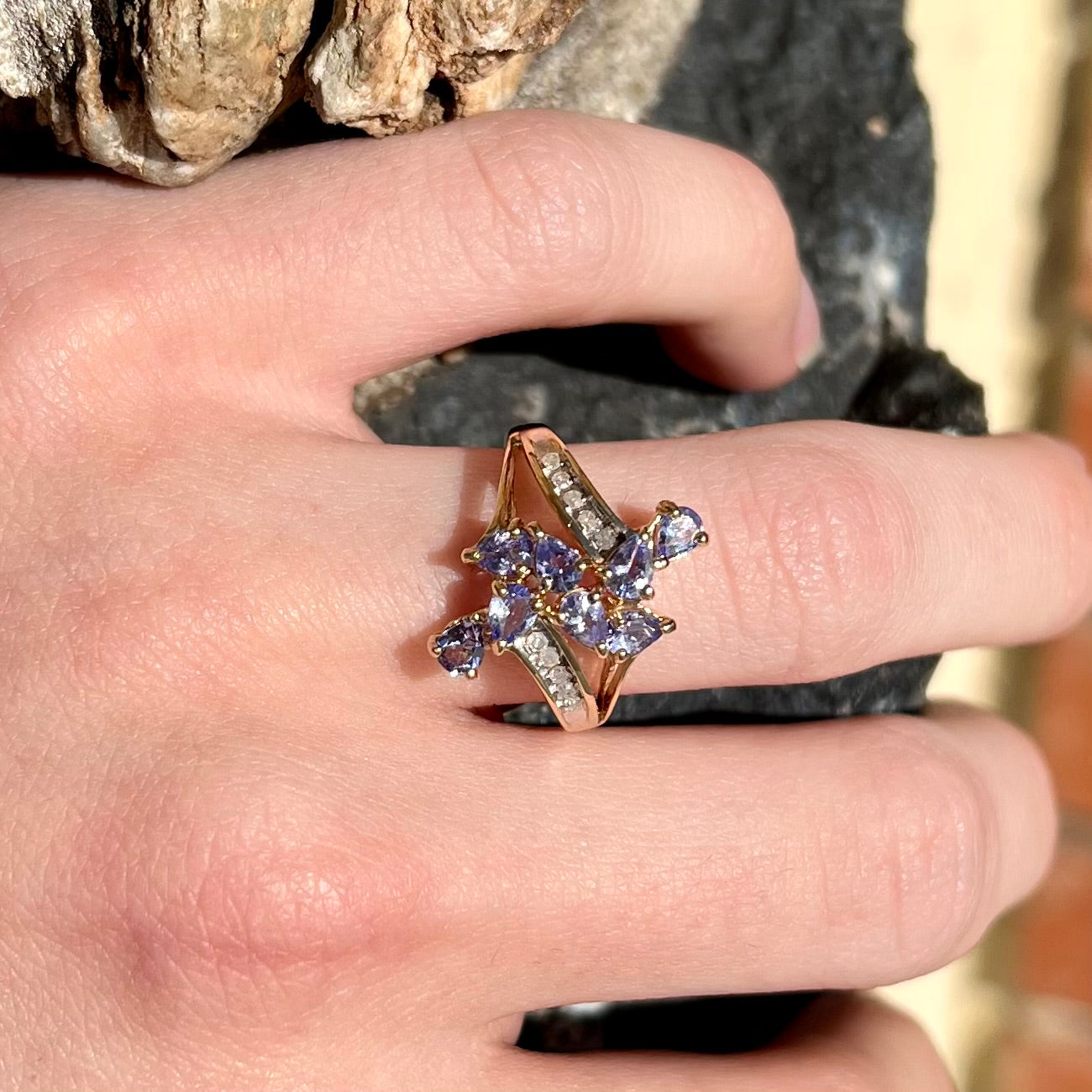 A pear shape tanzanite cluster ring channel set with diamonds in yellow gold.