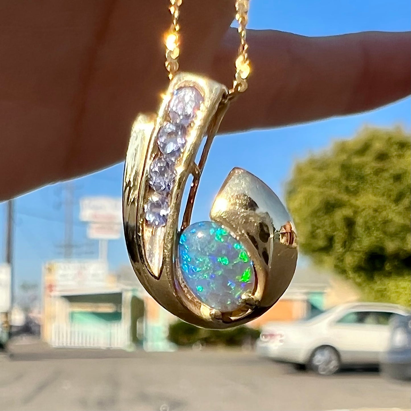 A Lightning Ridge black crystal opal necklace set with blue tanzanite in yellow gold.  Gold chain not included.