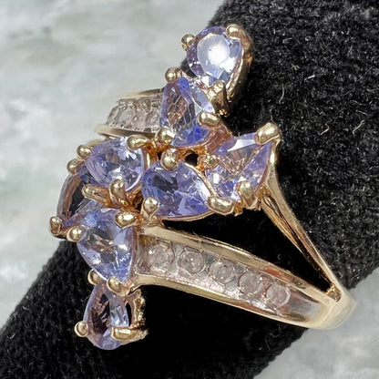 A pear shape tanzanite cluster ring channel set with diamonds in yellow gold.