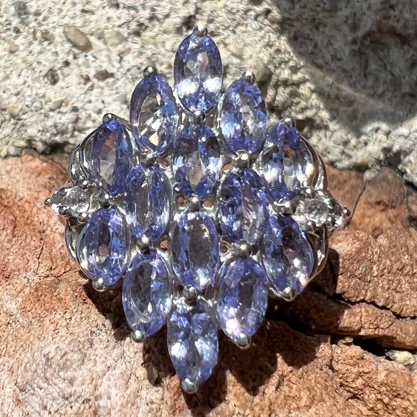 A sterling silver gemstone cluster ring set with oval cut tanzanite stones and round cubic zirconia accents.