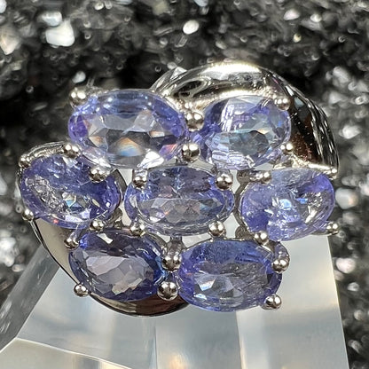 A sterling silver cluster ring prong set with seven faceted oval cut blue tanzanite stones.