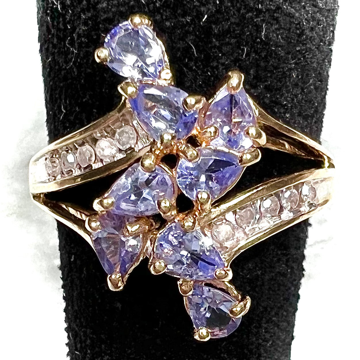A pear shape tanzanite cluster ring channel set with diamonds in yellow gold.