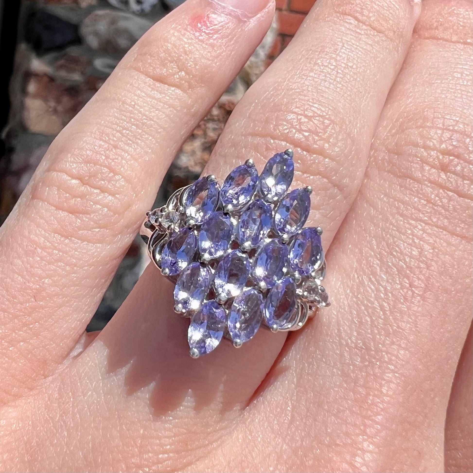 A sterling silver gemstone cluster ring set with oval cut tanzanite stones and round cubic zirconia accents.
