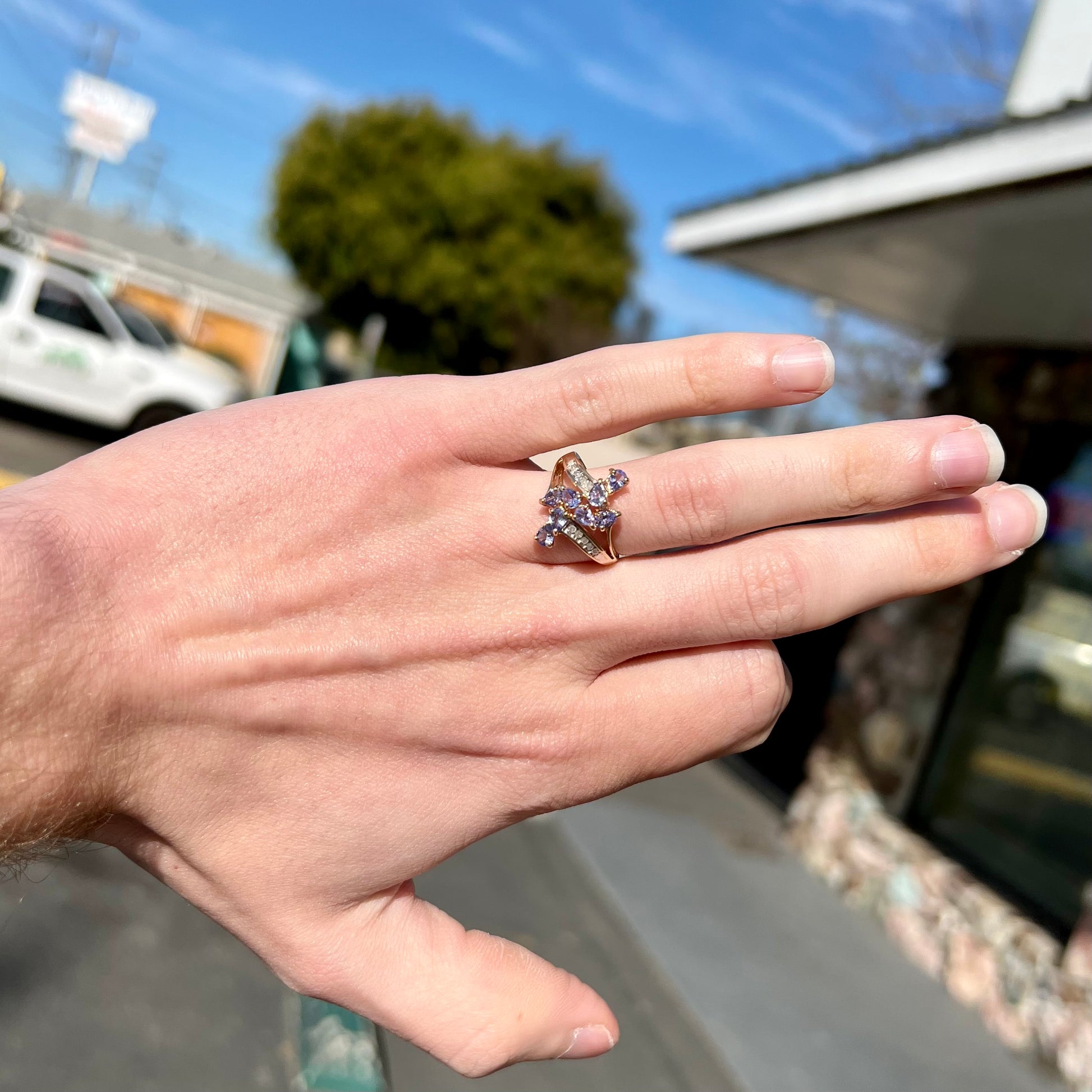 A pear shape tanzanite cluster ring channel set with diamonds in yellow gold.
