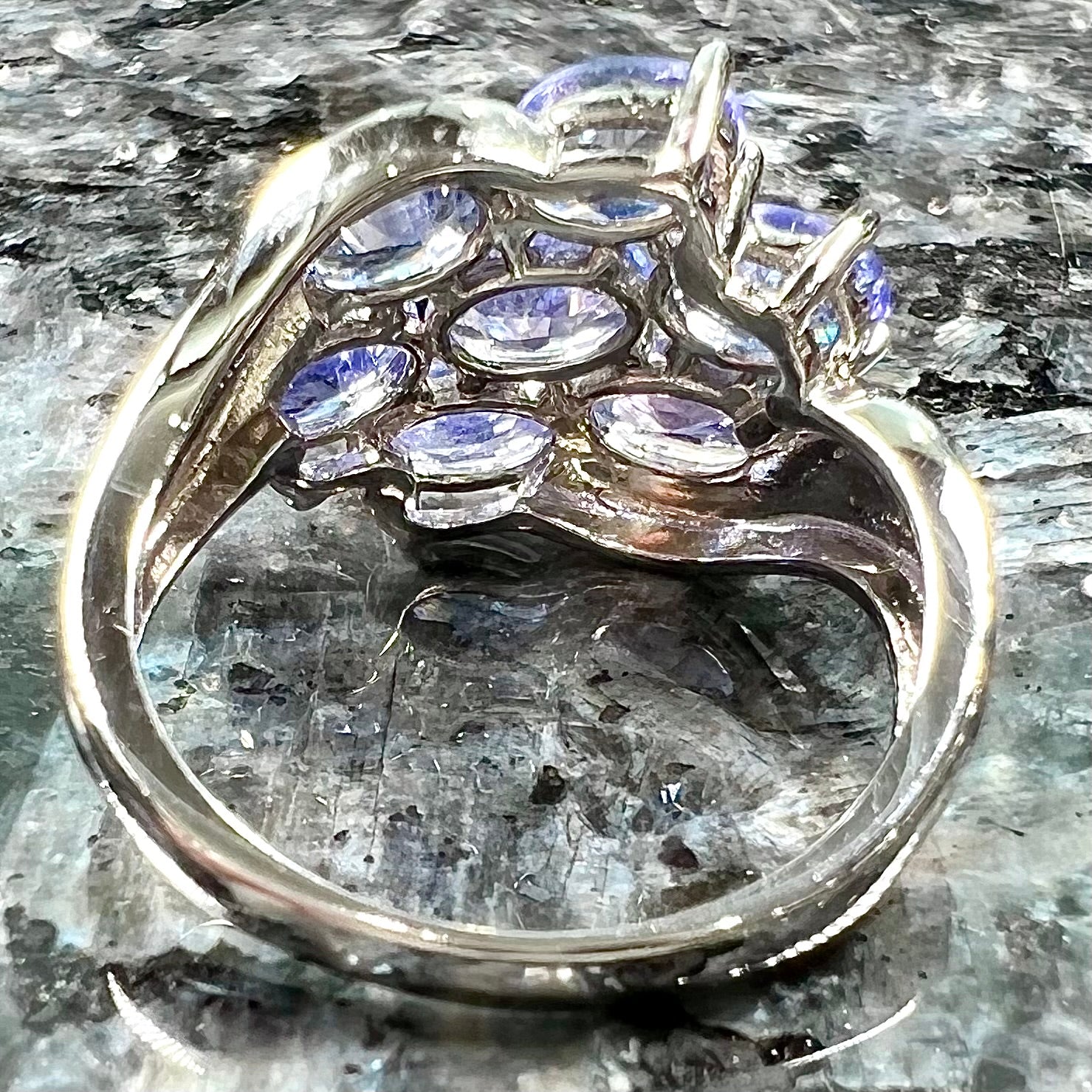 A sterling silver cluster ring prong set with seven faceted oval cut blue tanzanite stones.