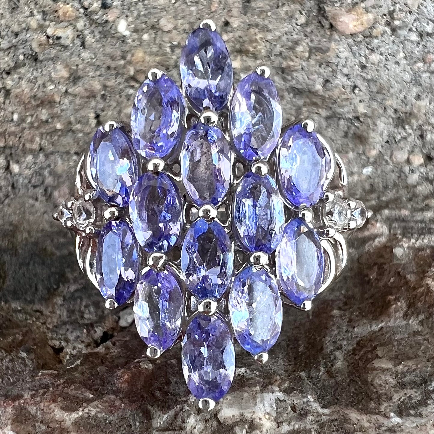 A sterling silver gemstone cluster ring set with oval cut tanzanite stones and round cubic zirconia accents.