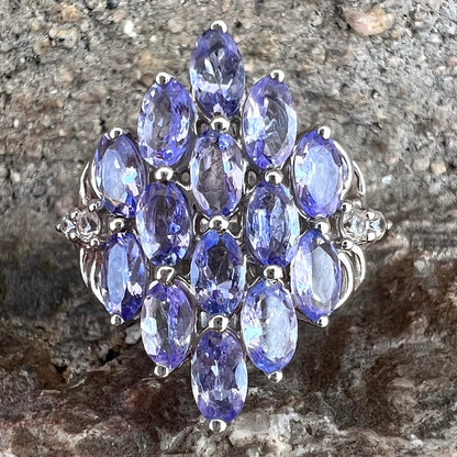 A sterling silver gemstone cluster ring set with oval cut tanzanite stones and round cubic zirconia accents.