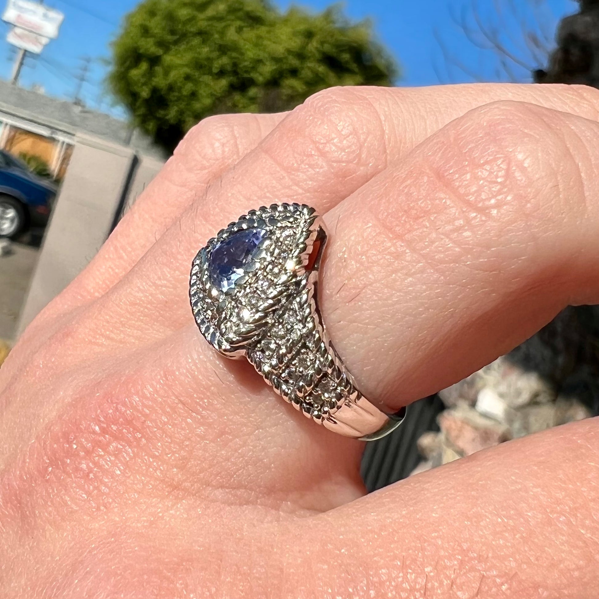 A white gold trillion cut tanzanite ring set with a diamond halo and diamond accents.