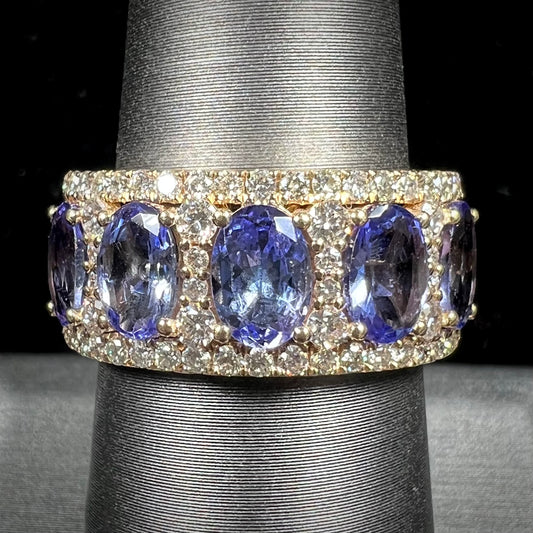 A gold and diamond ladies' band set with five oval cut tanzanite stones.