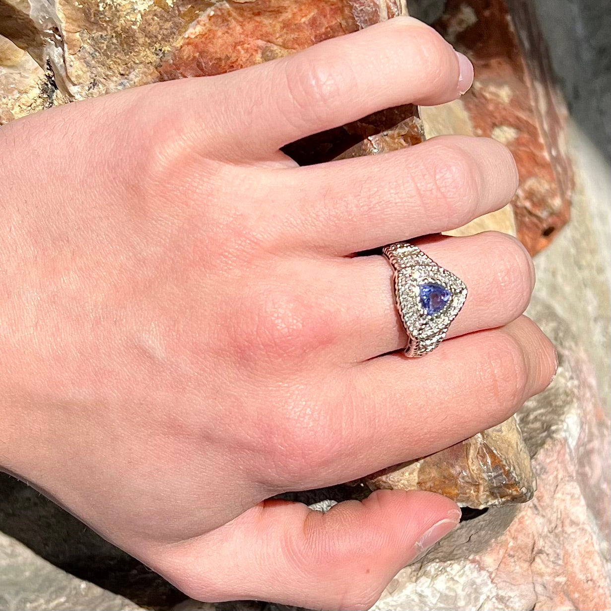 A white gold trillion cut tanzanite ring set with a diamond halo and diamond accents.