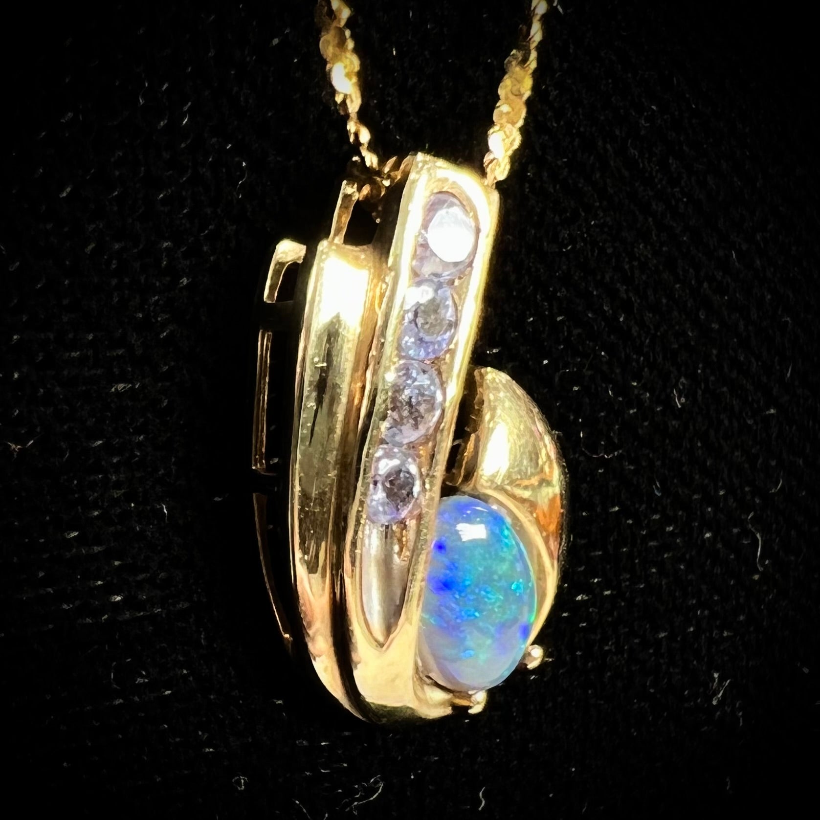 A Lightning Ridge black crystal opal necklace set with blue tanzanite in yellow gold.  Gold chain not included.