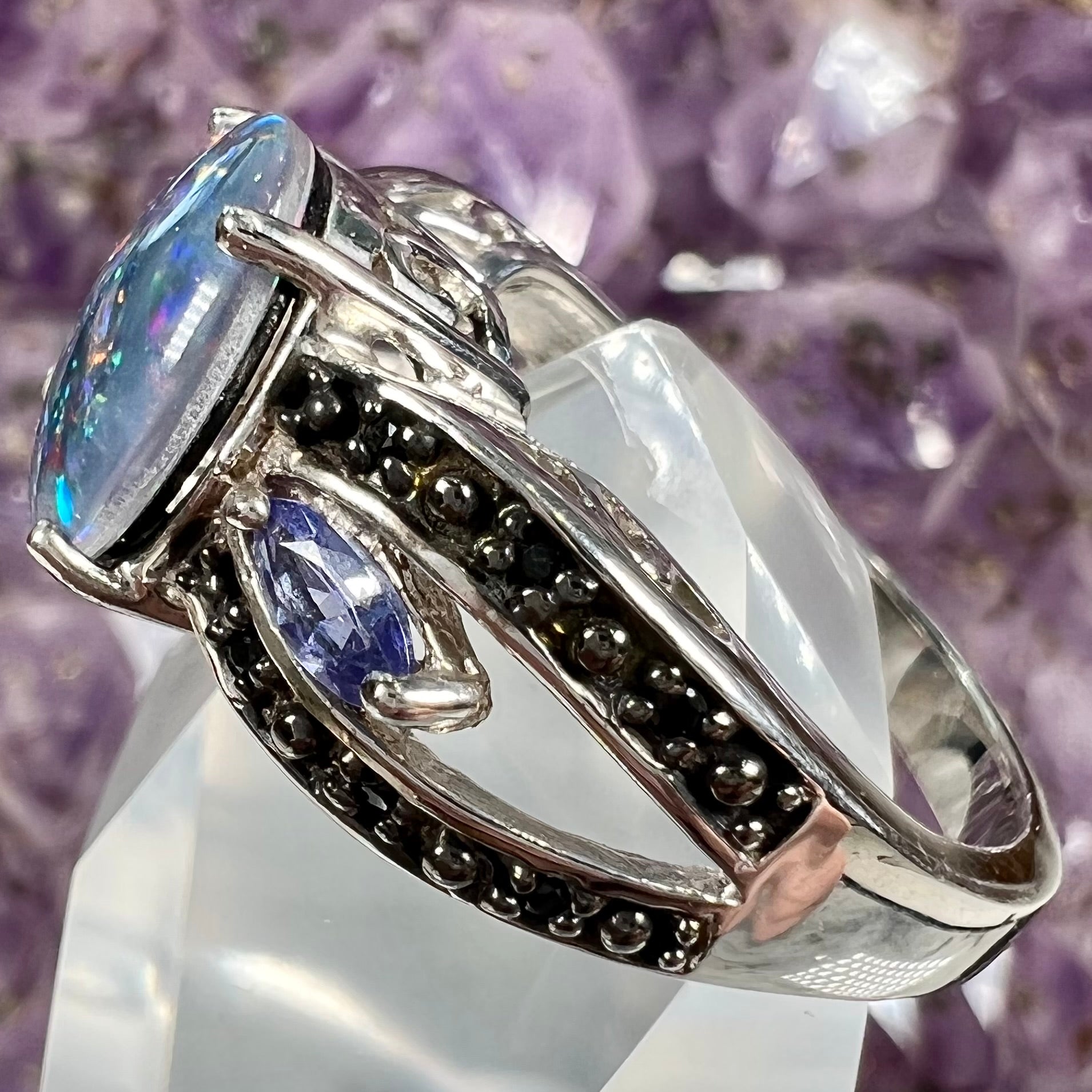 A sterling silver black opal triplet ring set with black spinel and marquise cut tanzanite accent stones.