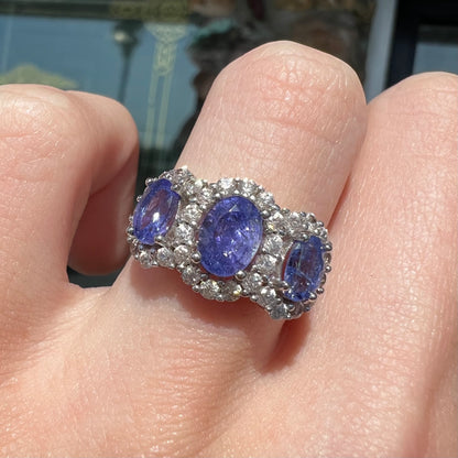 A sterling silver past, present, future three stone tanzanite ring.  The main stones are set in a halo of cubic zirconia.