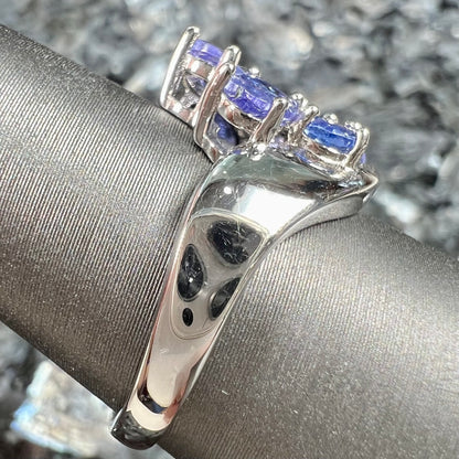 A sterling silver cluster ring prong set with seven faceted oval cut blue tanzanite stones.
