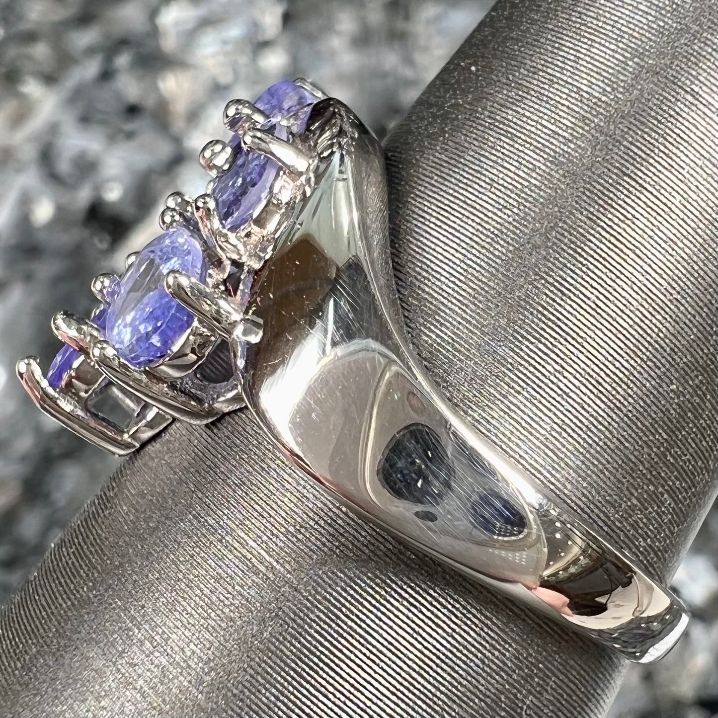 A sterling silver cluster ring prong set with seven faceted oval cut blue tanzanite stones.