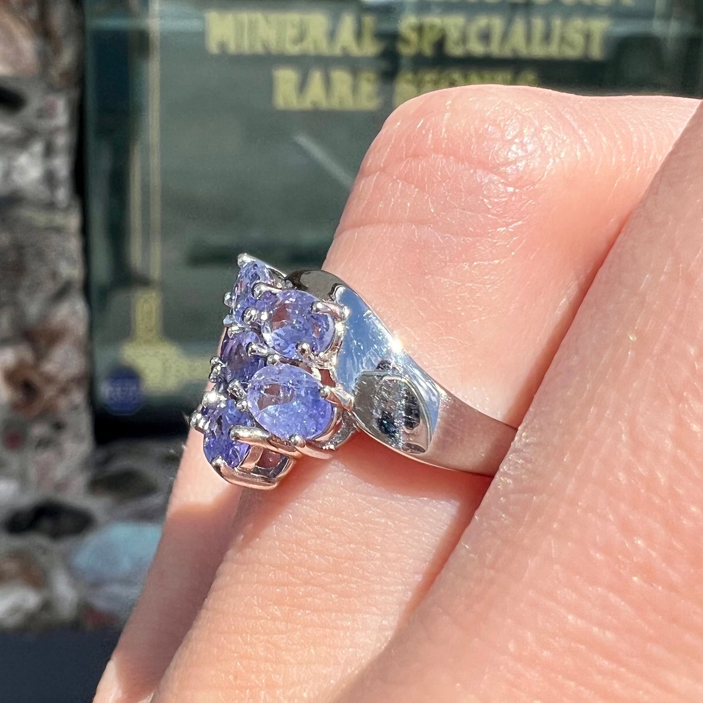 A sterling silver cluster ring prong set with seven faceted oval cut blue tanzanite stones.