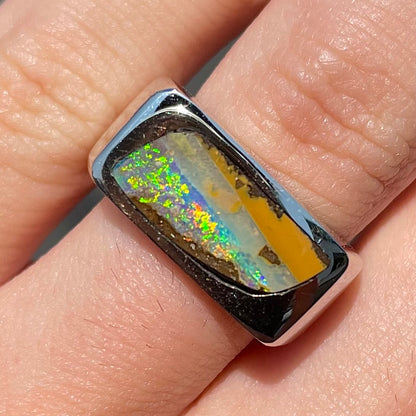A white gold flush set boulder opal solitaire ring.  The style is unisex.
