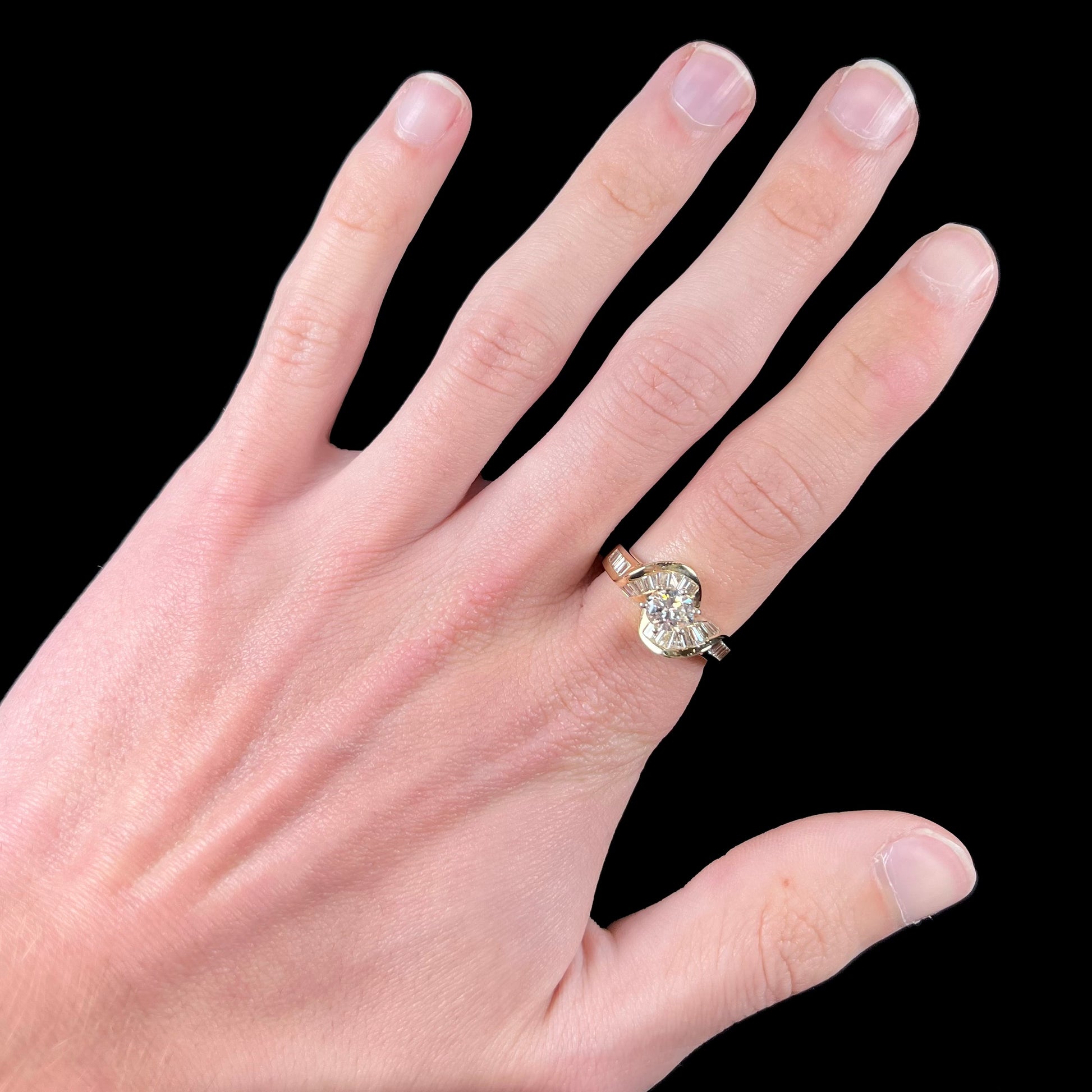 A ladies' yellow gold engagement ring set with a 0.77ct oval cut diamond and baguette cut diamond accents.