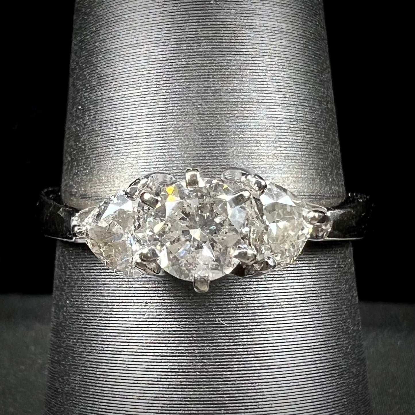 A ladies' three stone diamond ring.  The center diamond is a round brilliant cut, and the two accents are heart shaped diamonds.