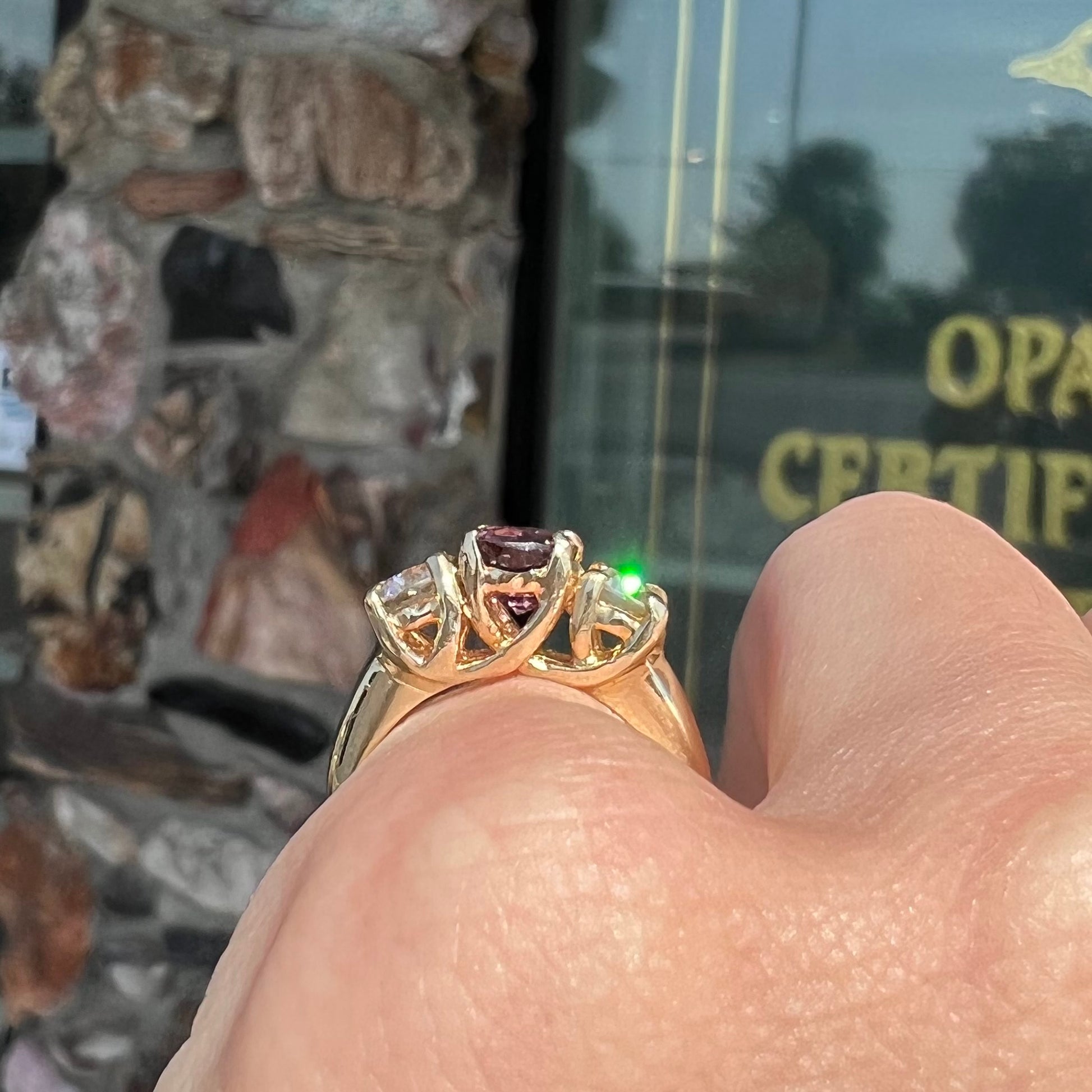 A yellow gold three stone ring set with two round cut white zircons and one cushion cut purple spinel.