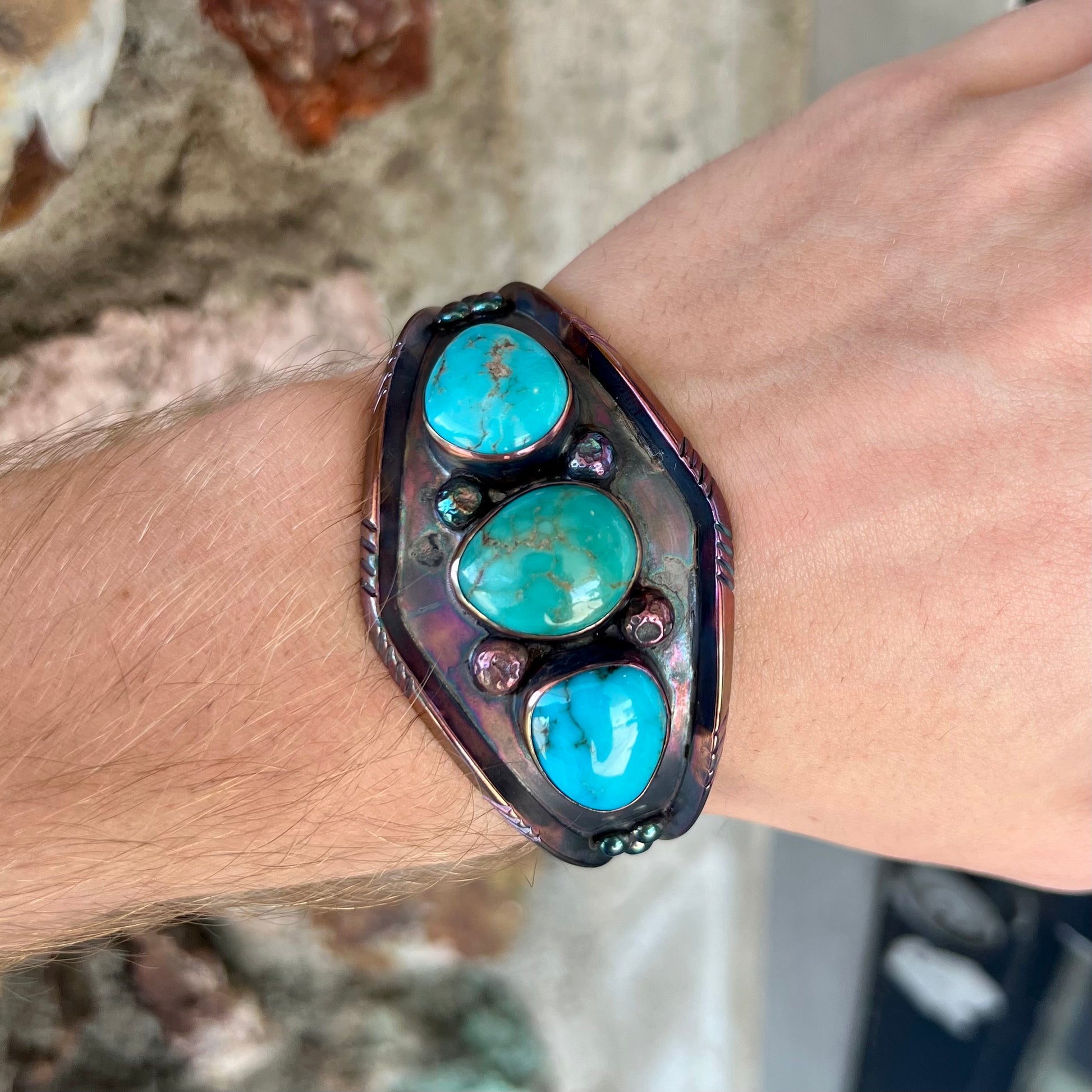A men's Navajo three stone turquoise cuff bracelet handmade by artist, Dean Brown.  The silver has an iridescent purple patina.