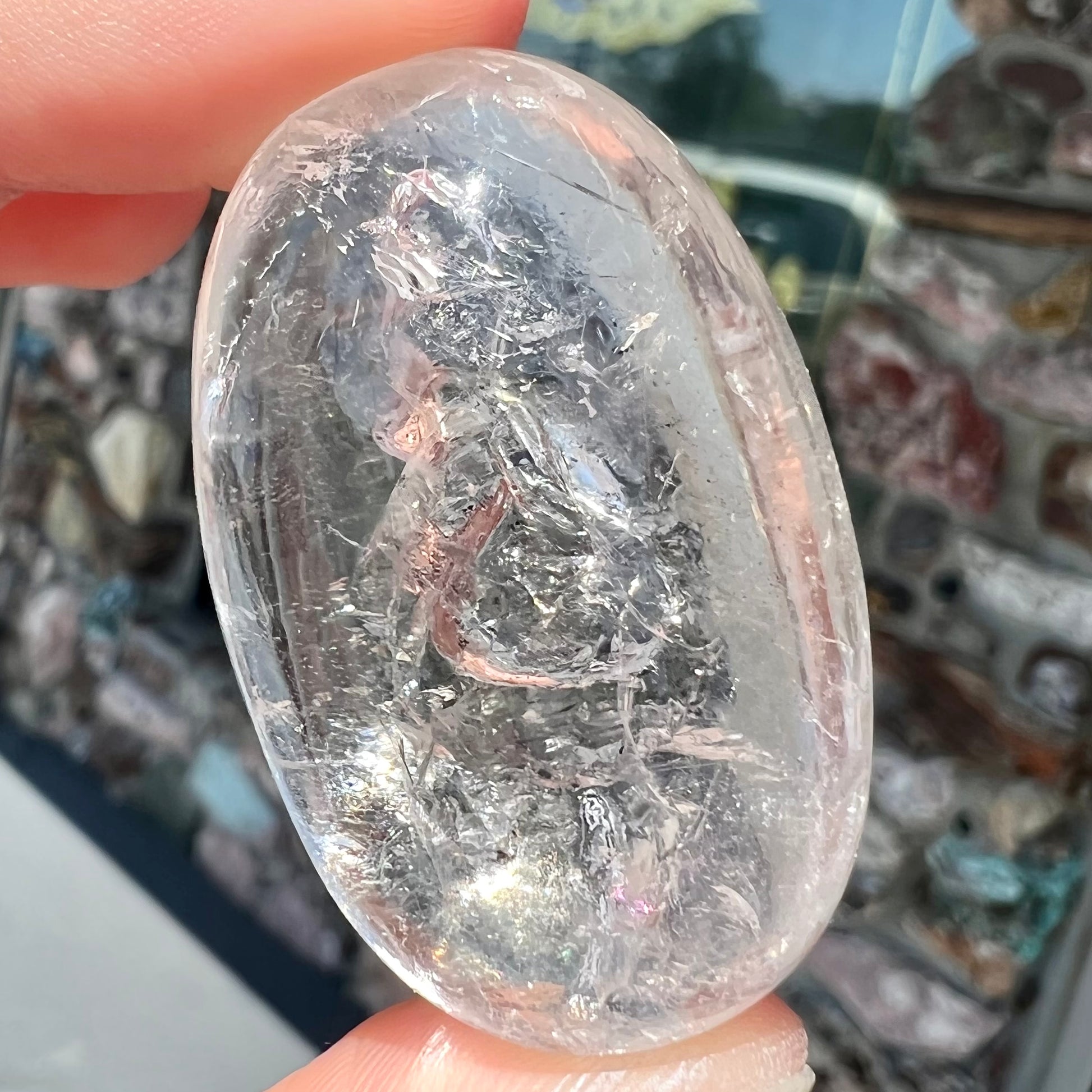 A polished clear quartz with two liquid enhydro inclusions around a solid phantom crystal inclusion.