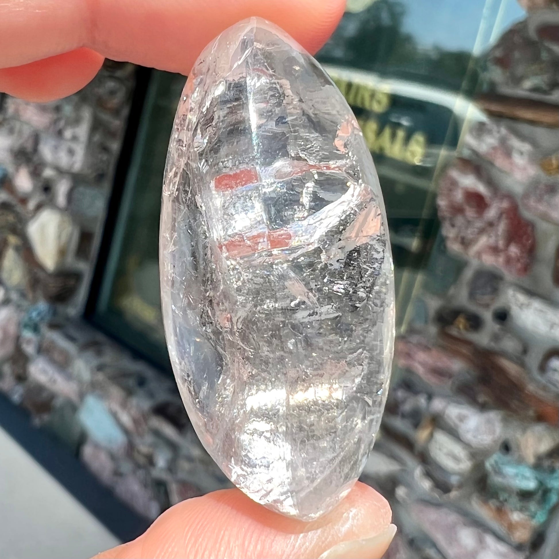 A polished clear quartz with two liquid enhydro inclusions around a solid phantom crystal inclusion.