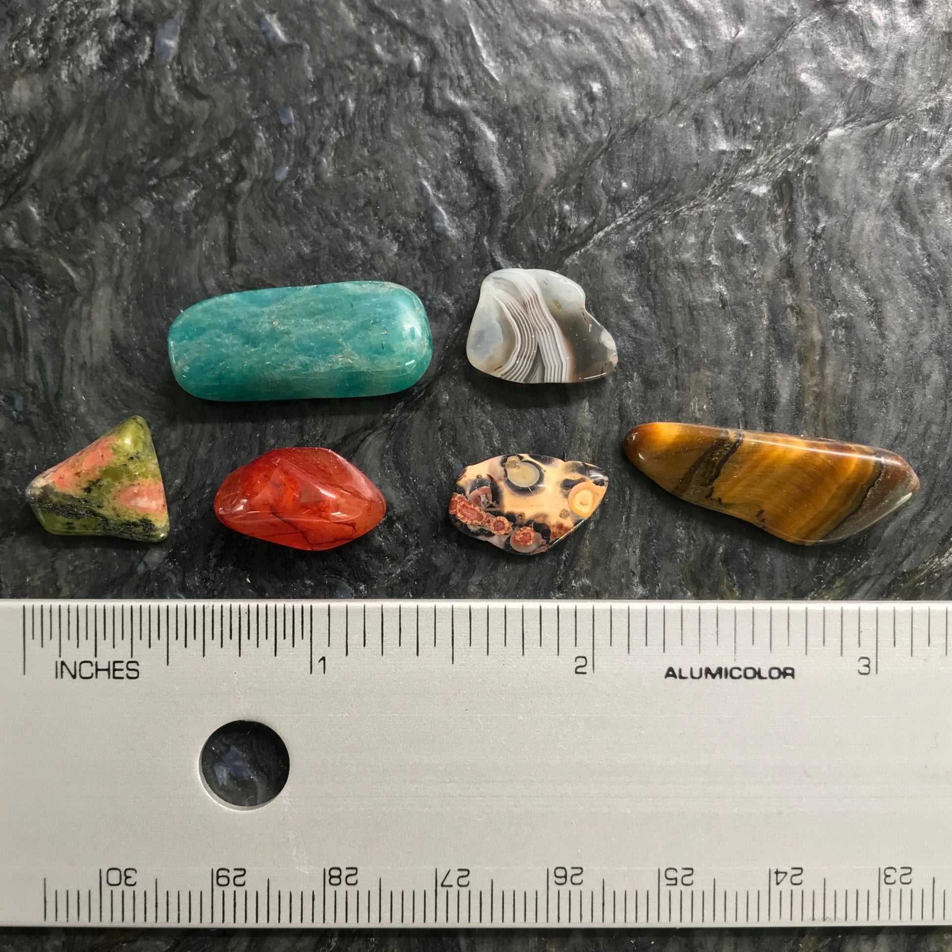 Small tumbled stone chips compared to a ruler.  Average size half an inch to one inch.