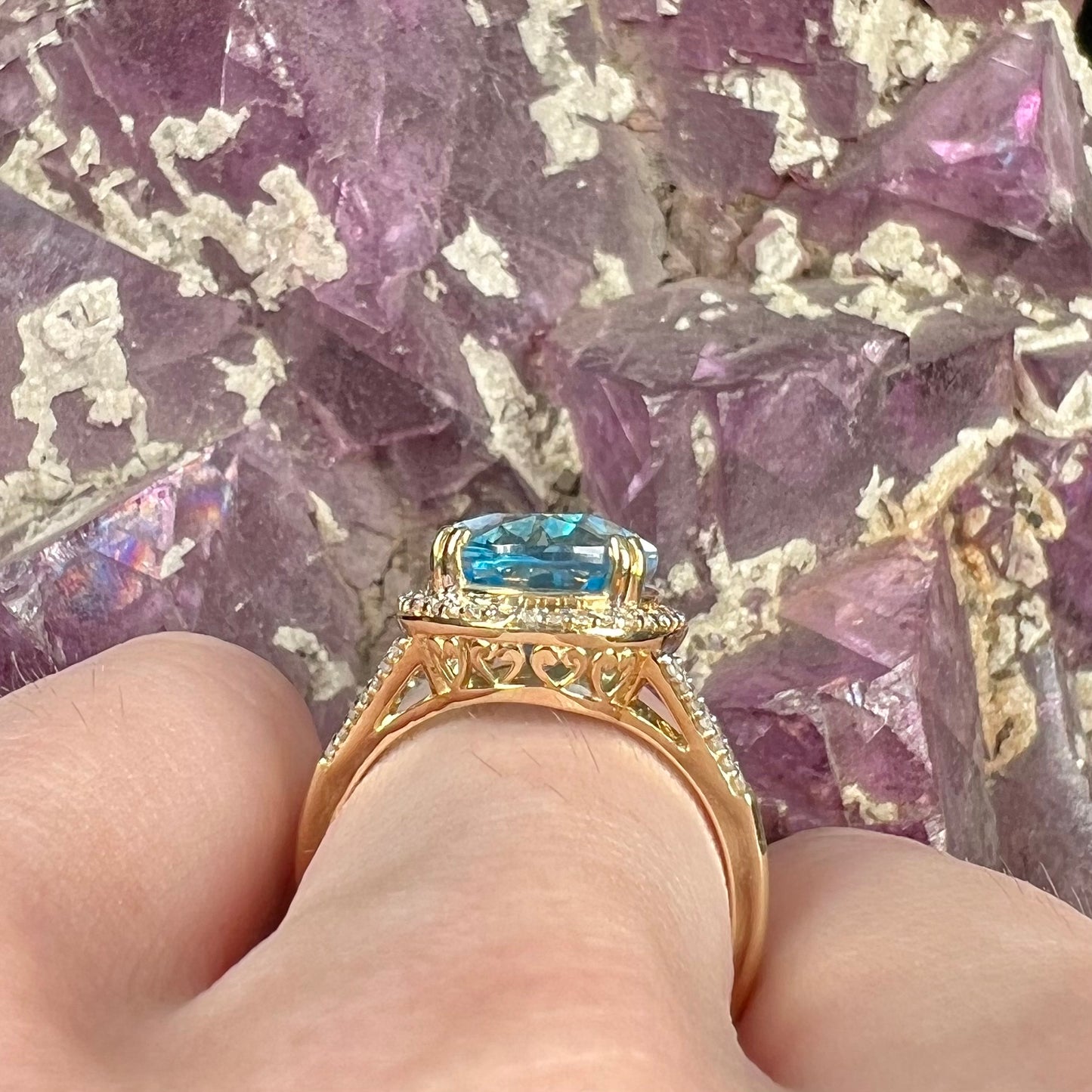 An oval cut Swiss blue topaz and diamond pave split shank ring in yellow gold.