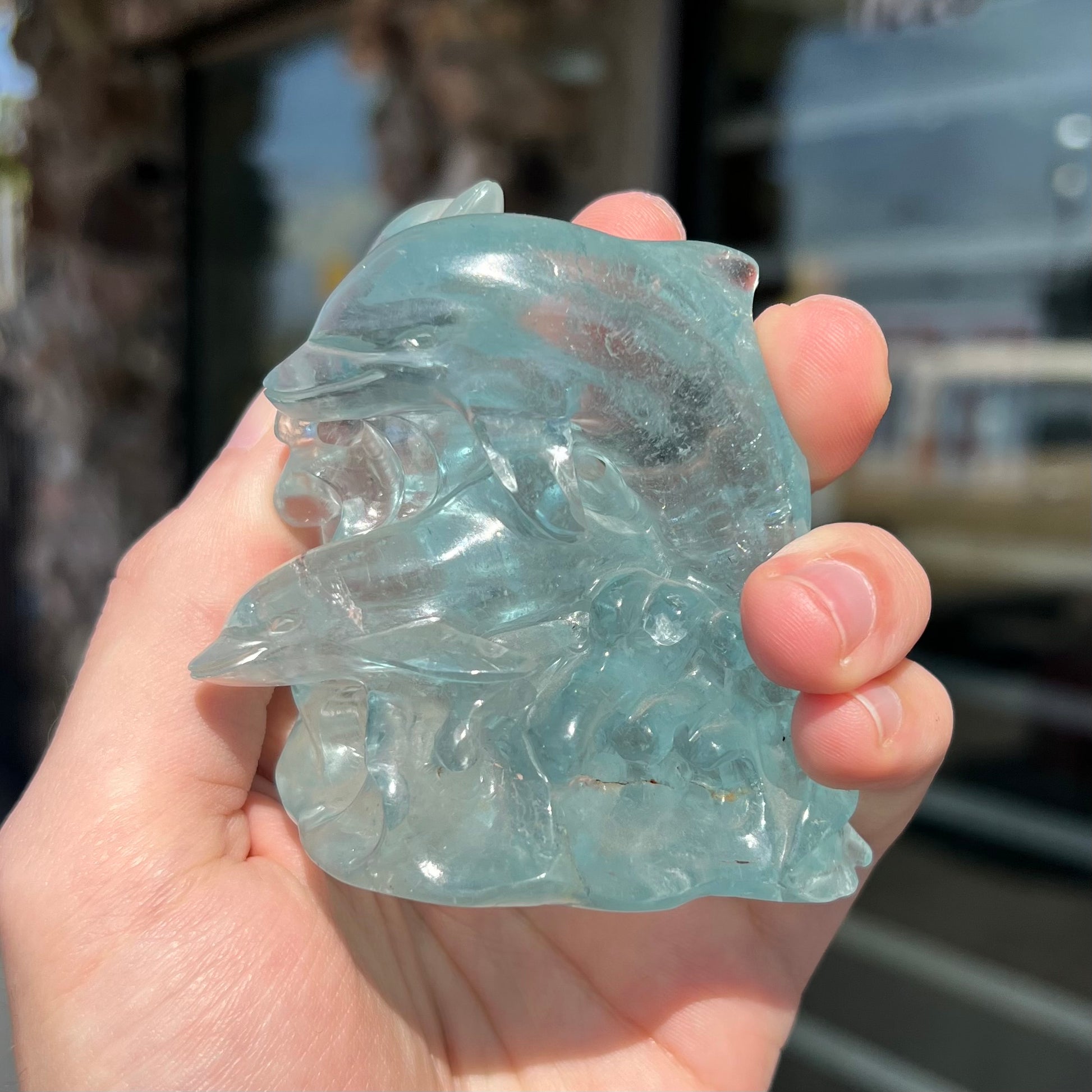 Three swimming dolphins carved from sky blue topaz crystal by artist, Ronald Stevens.