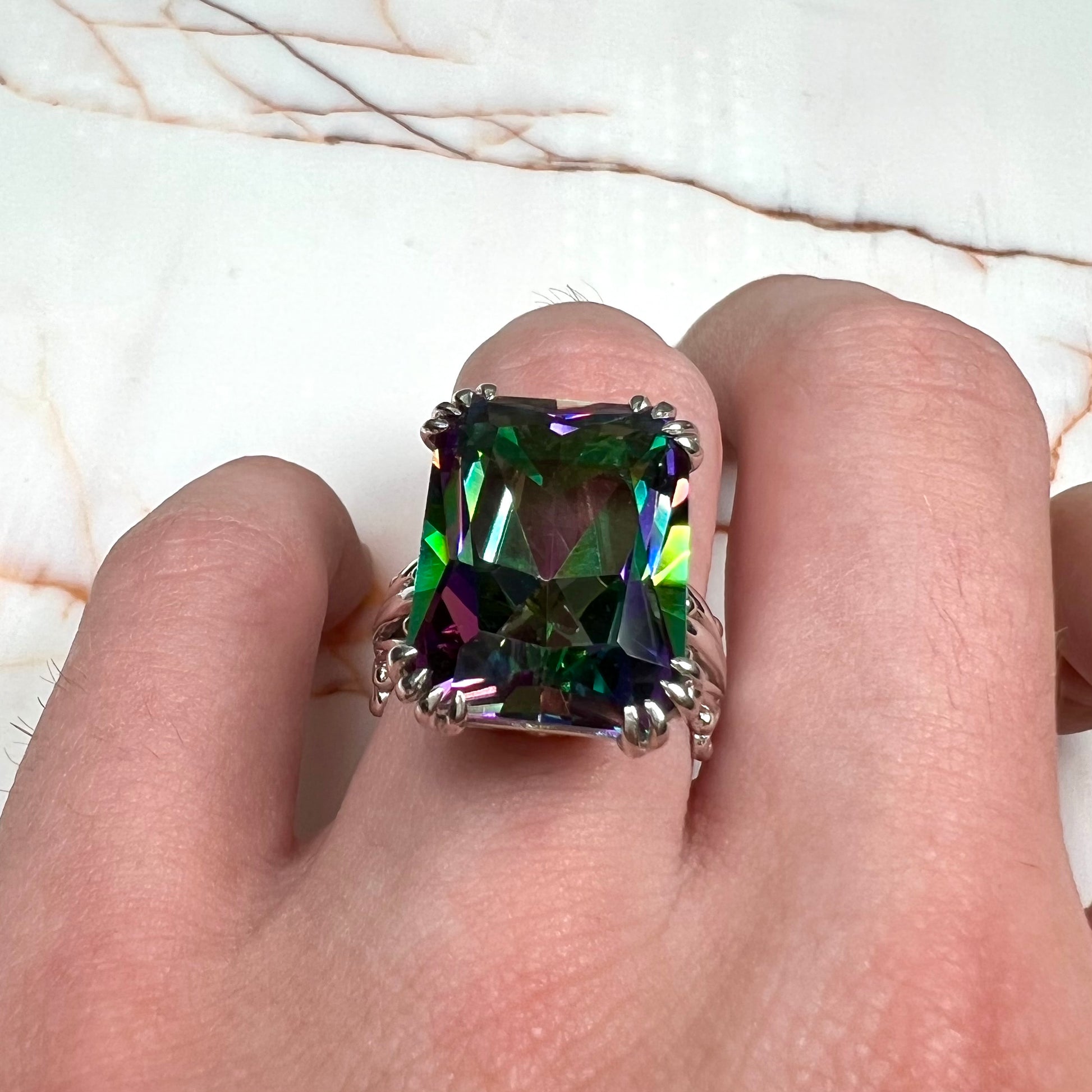 Emerald cut mystic topaz prong set in a decorative sterling silver ring.