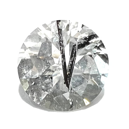 A faceted round brilliant cut clear quartz stone with black tourmaline inclusions.  Inclusions appear like a clock's hands.