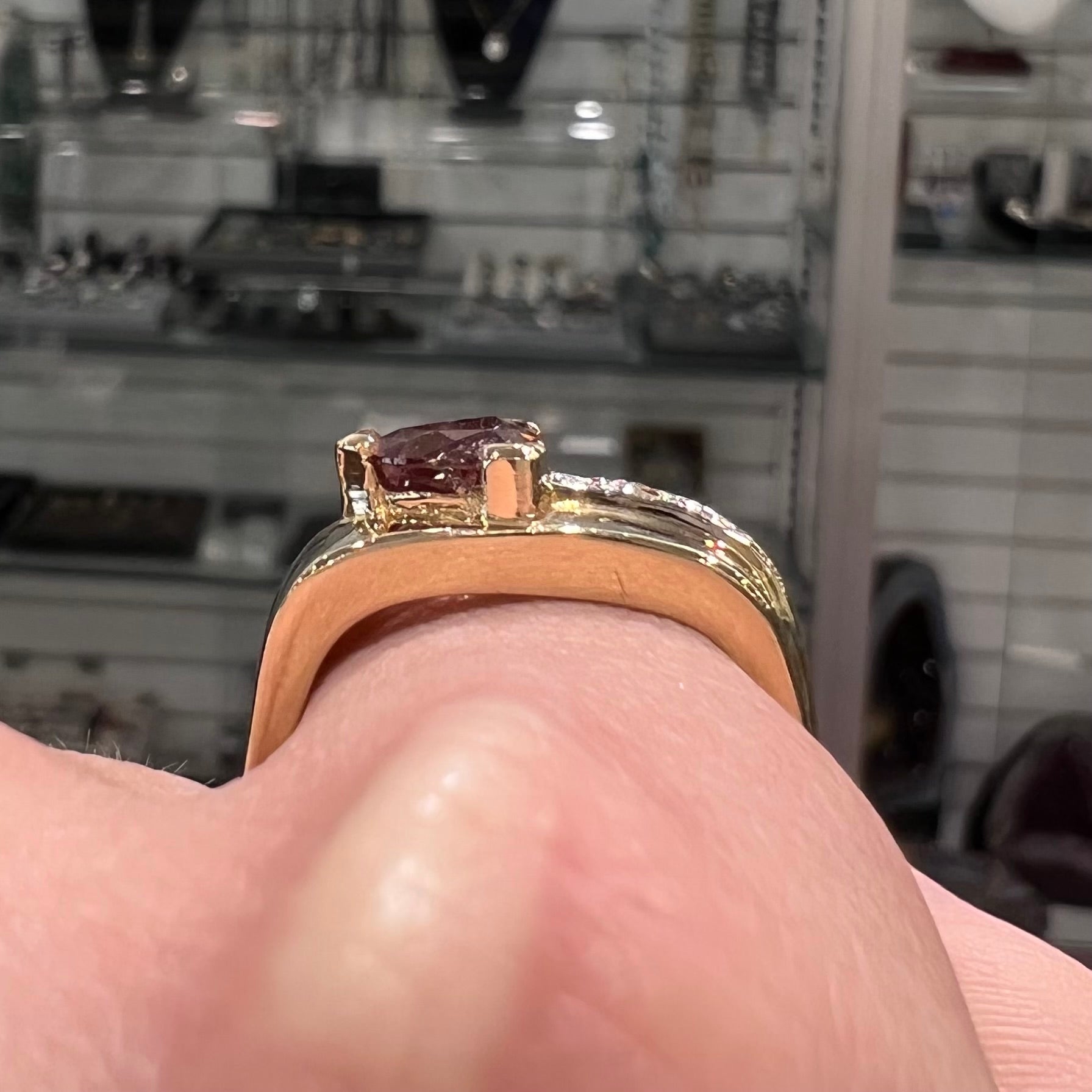 A men's gold pink tourmaline ring.  Set next to the trillion cut tourmaline is a row of three round white sapphires.