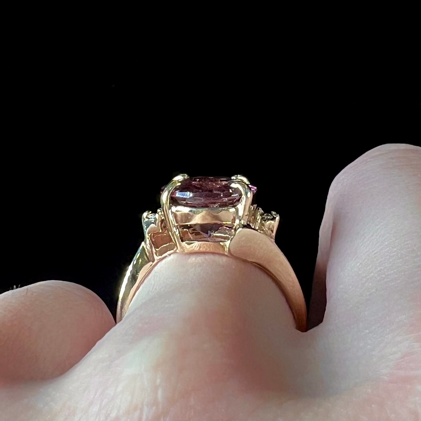 A ladies' yellow gold, faceted oval cut purple tourmaline ring set with diamond accents.
