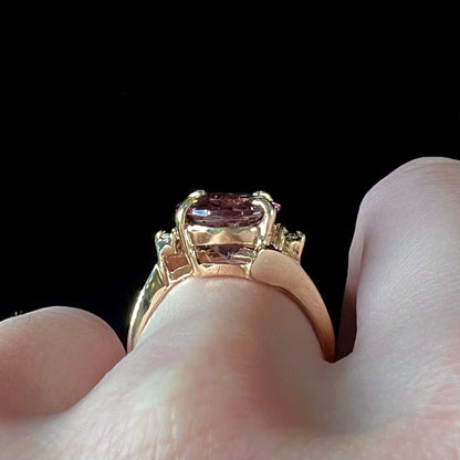 A ladies' yellow gold, faceted oval cut purple tourmaline ring set with diamond accents.