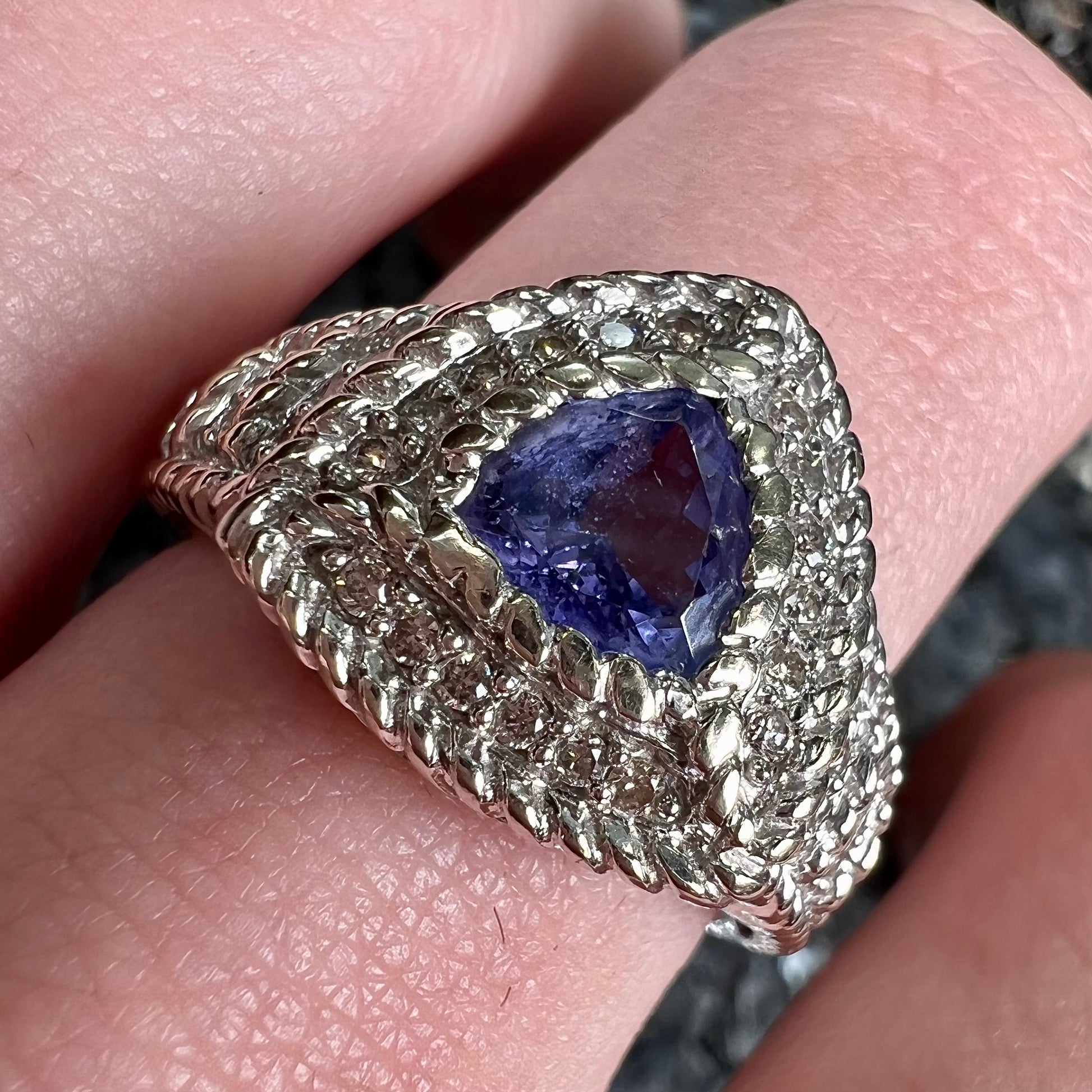 A white gold trillion cut tanzanite ring set with a diamond halo and diamond accents.