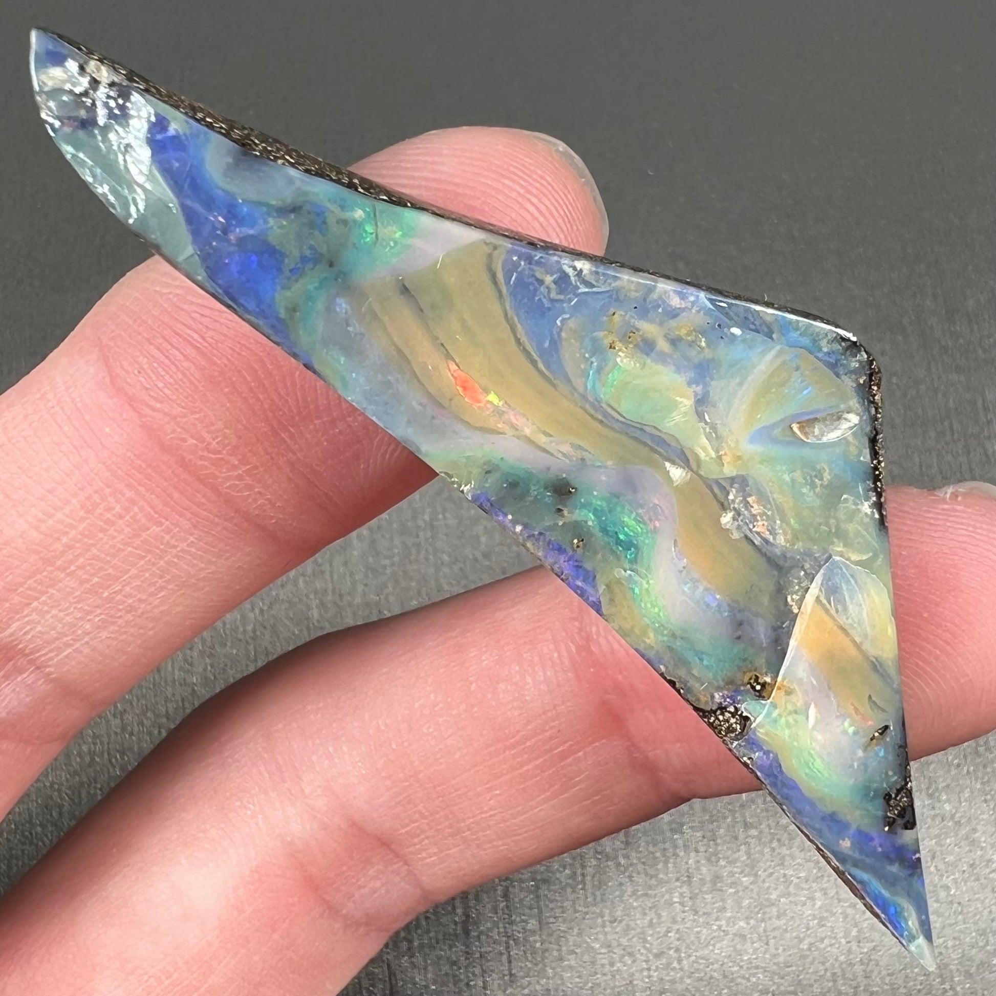 A loose, triangular shaped boulder opal stone from Queensland, Australia.