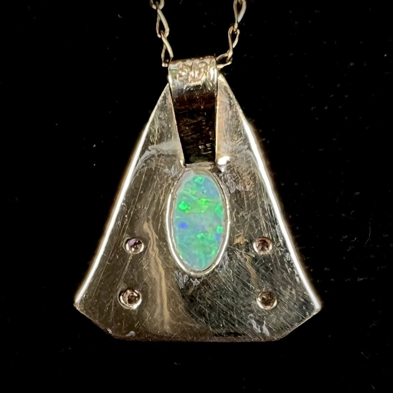 A triangular gold pendant set with five round diamonds and a white crystal opal with green fire.