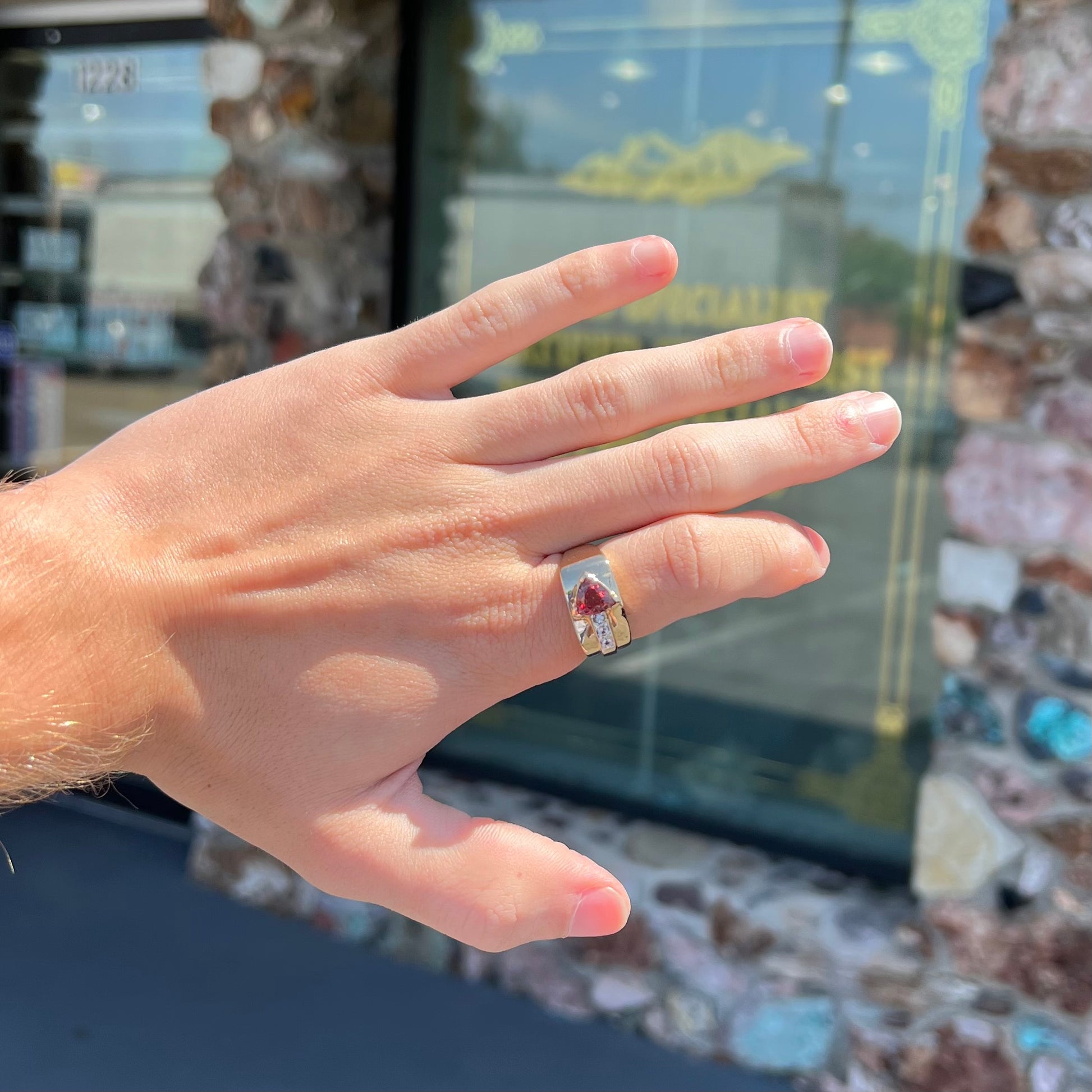 A men's gold pink tourmaline ring.  Set next to the trillion cut tourmaline is a row of three round white sapphires.