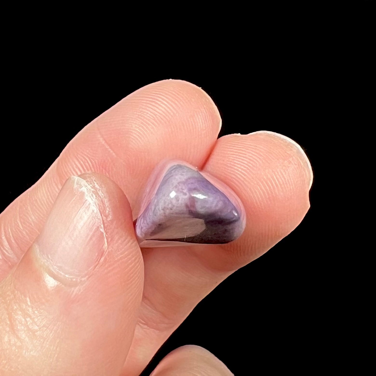 A tumble polished piece of speckled turkiyenite stone, also known as Turkish purple jade.