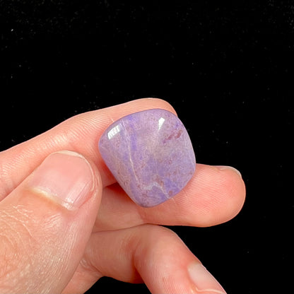 A tumbled turkiyenite jade stone from Bursa, Turkey.  The rock is purple with red speckles.