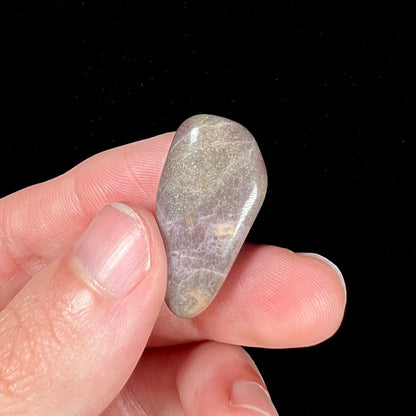 A tumbled turkiyenite purple jade stone.  The rock has a green tint from an epidote matrix.