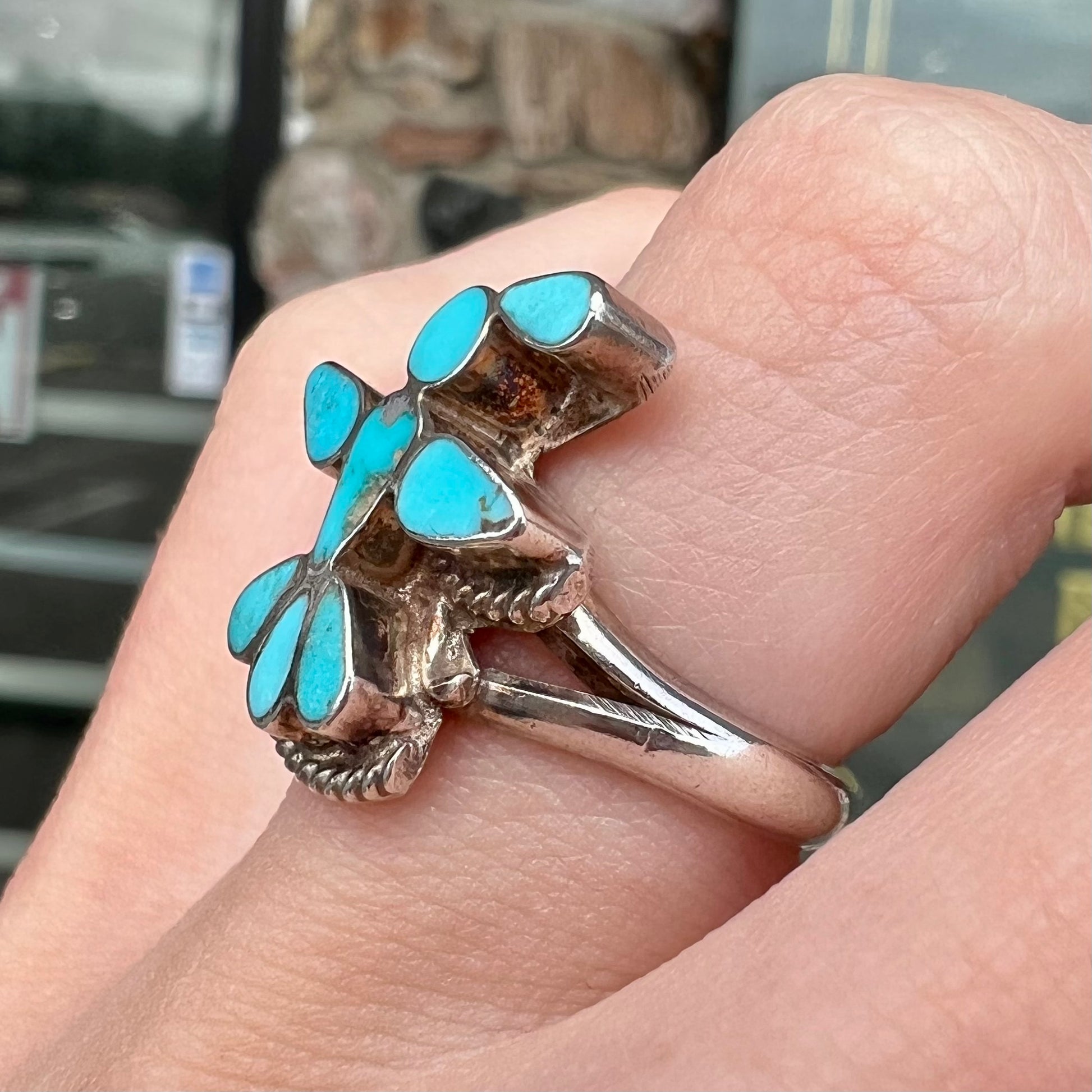 A sterling silver and turquoise inlay ring.  The ring is in the shape of a Native American thunderbird.