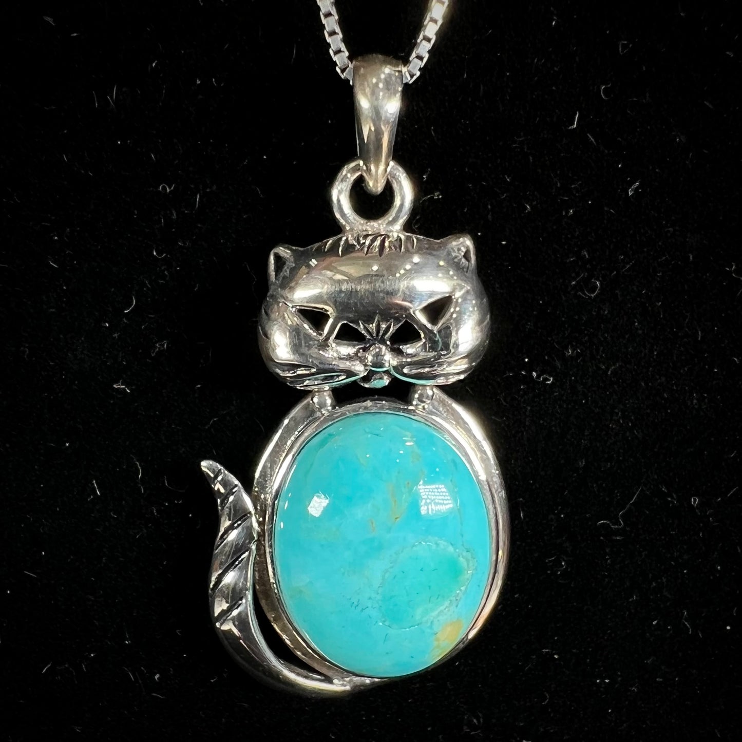 A sterling silver cat necklace set with an oval cut Sleeping Beauty turquoise stone.