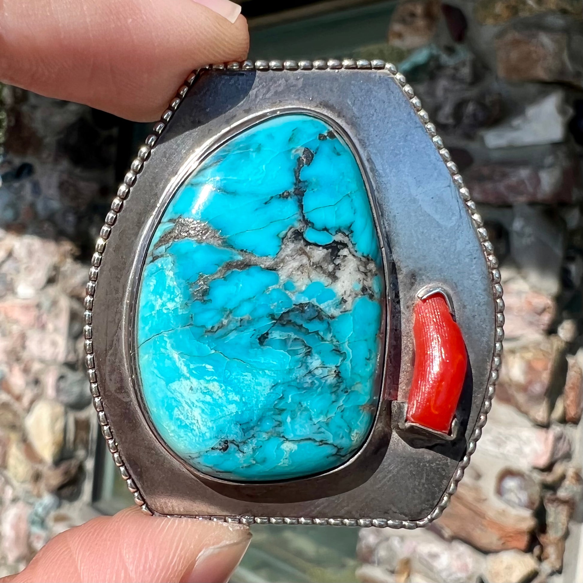 A sterling silver turquoise and polished coral branch pendant.  The back of the piece is signed "A.H."