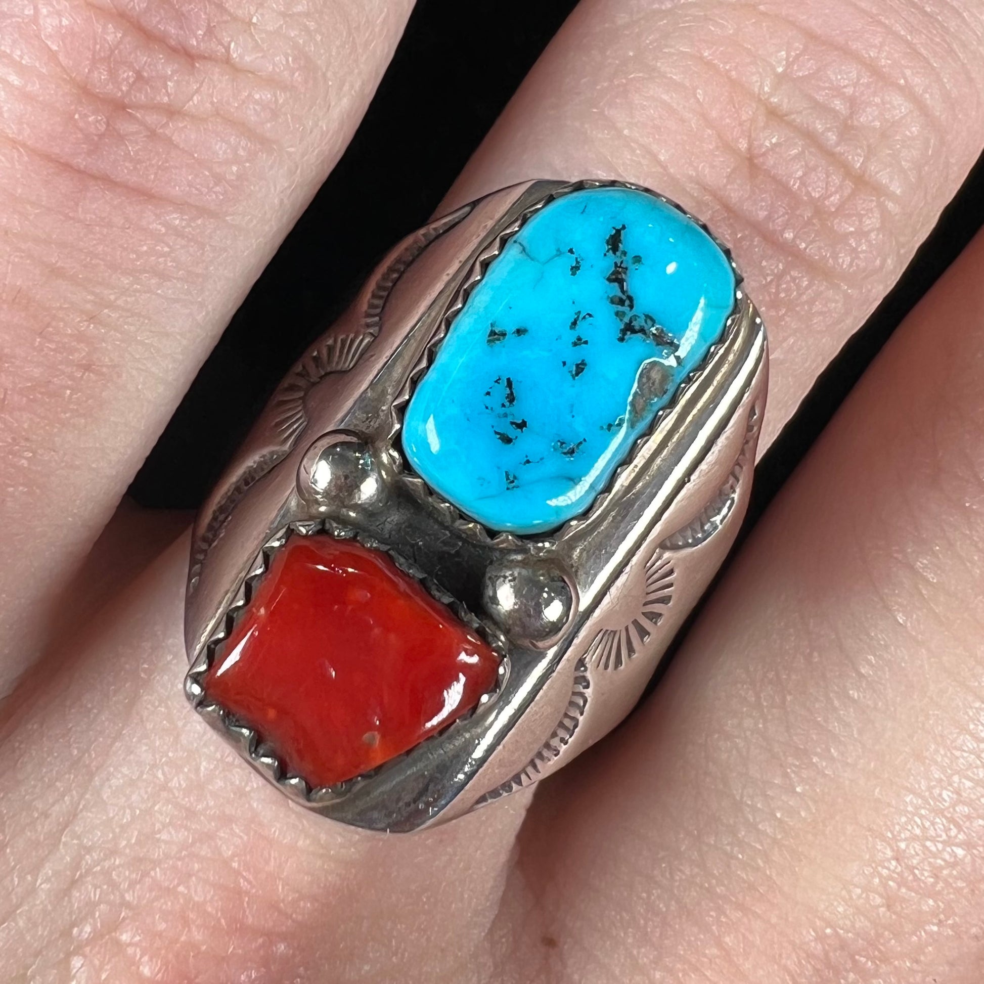 A men's sterling silver Navajo ring set with turquoise and red coral stones.
