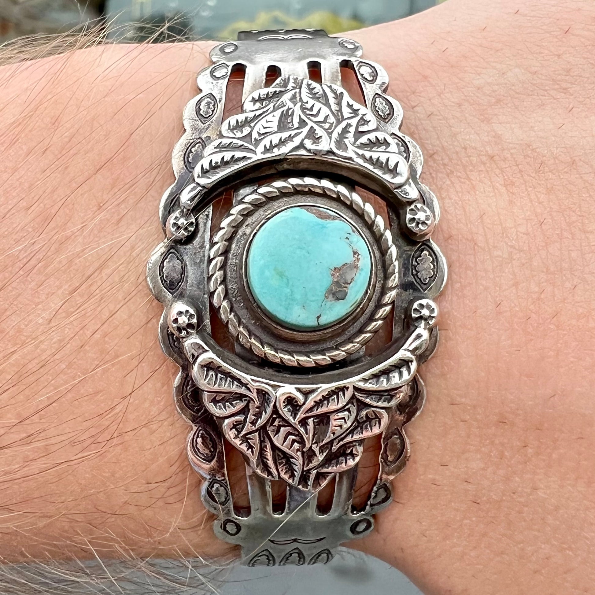 A base metal cuff bracelet set with a round cabochon cut imitation blue turquoise stone.
