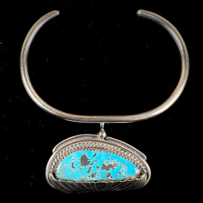 A sterling silver cuff bracelet with an attached dangle segment set with a turquoise stone from Pinto Valley.